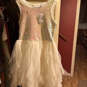 Pink sequins on top of sleeveless flowing white netting at bottom .